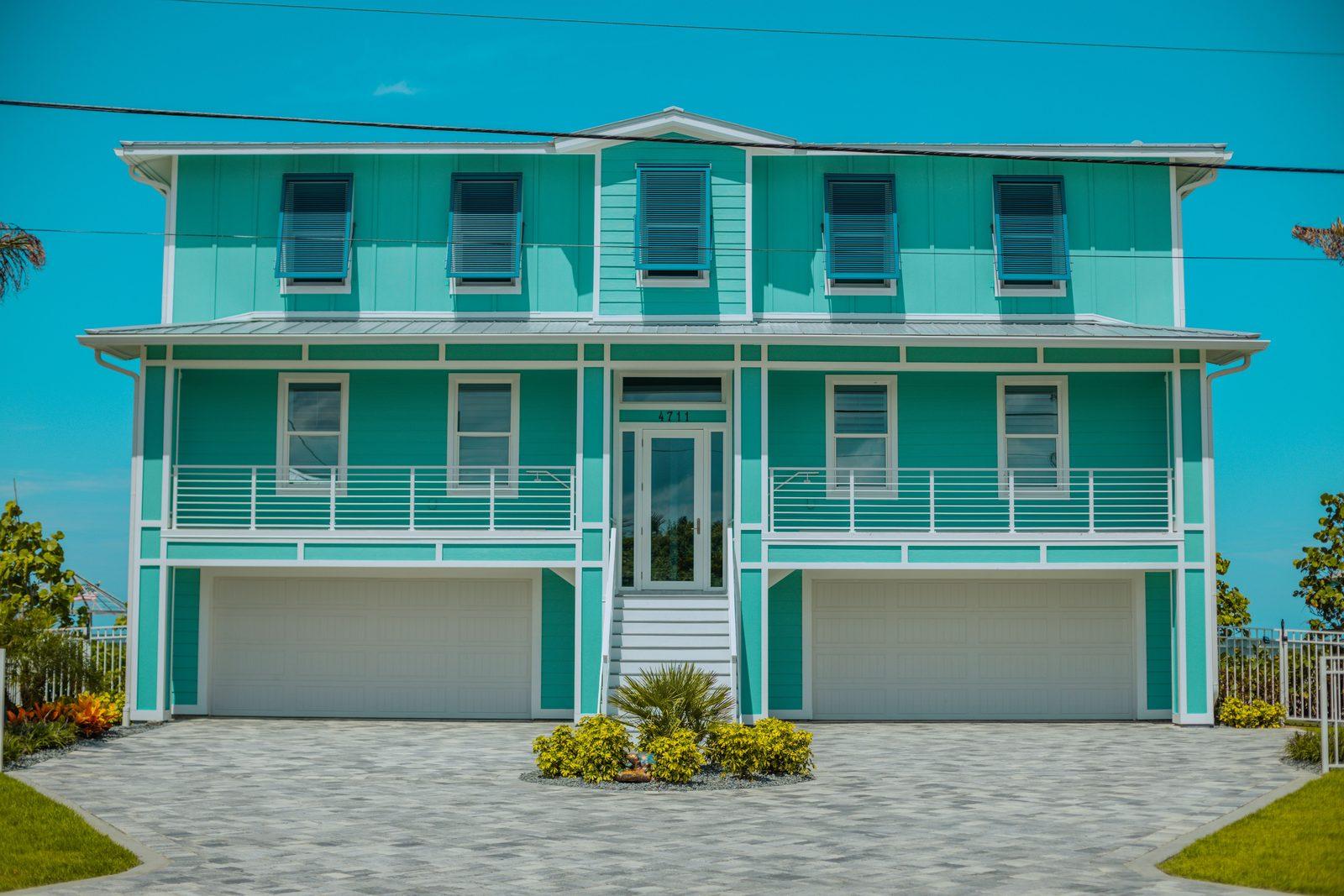 A two-storey Florida coastal townhome with balconies, shutters and a paver driveway